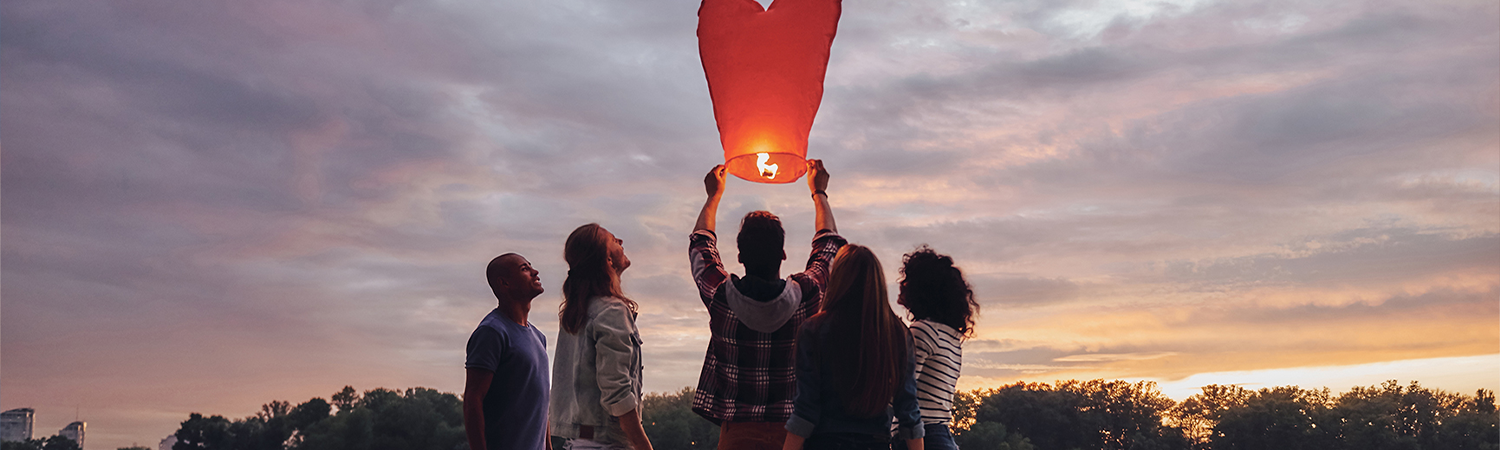 people preparing a heart-shaped sky lantern for flight